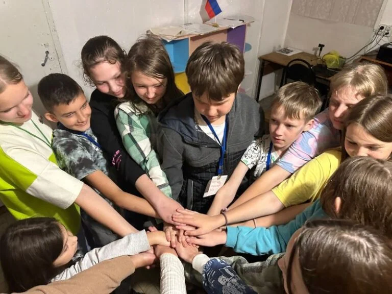 Школьники складывают руки вместе во время группового упражнения
